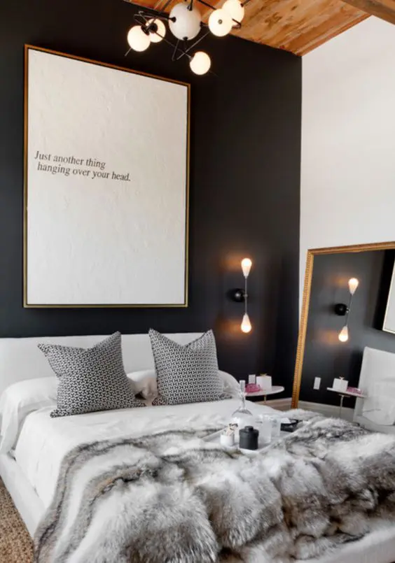 a luxurious bedroom with a black headboard wall, a large framed mirror and unique lighting fixtures