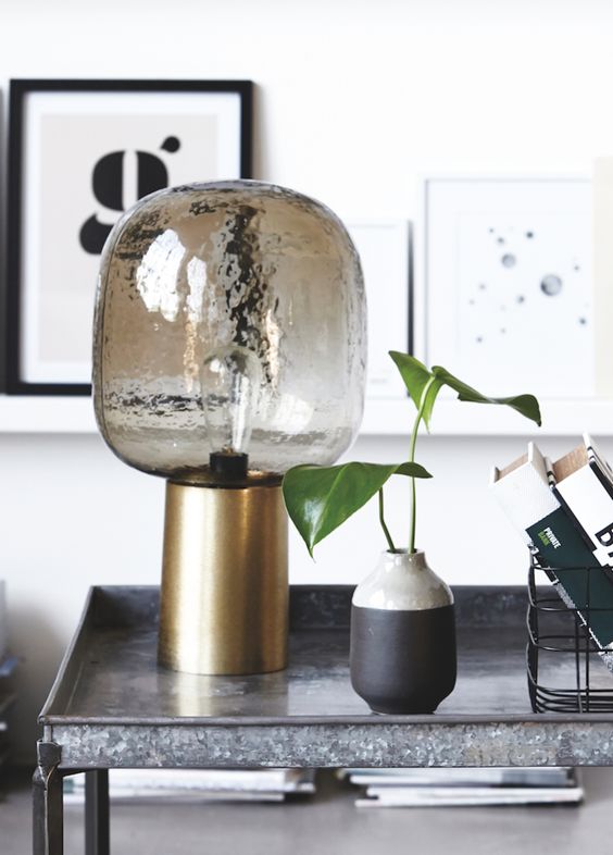 a smoked glass lamp with a brass base looks very chic and will give much light due to the clear glass