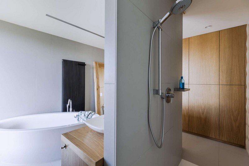 The master bathroom features a free standing bathtub, a shower and some wooden touches for coziness