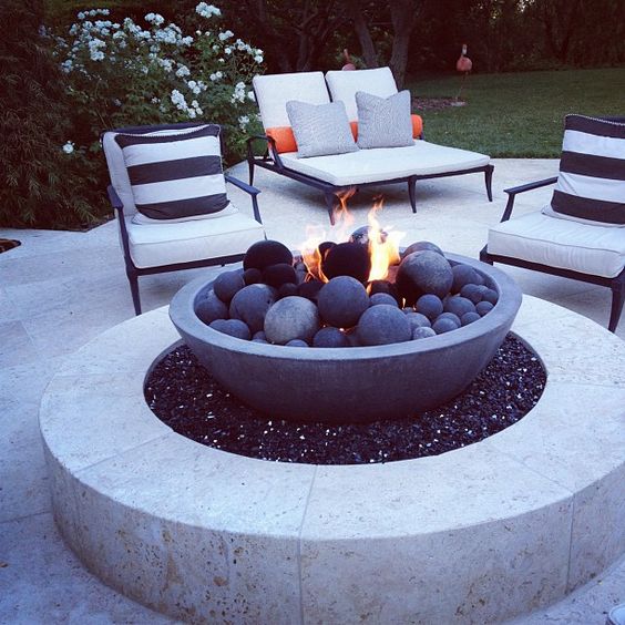 A modern bonfire space of white stone with an eye catchy firepit with stone balls