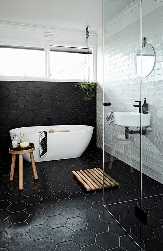 large scale black hex tiles cover the floor and go up the wall and contrast the white tiles