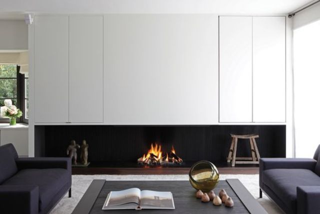A minimalist living room with a built in fireplace under the cabinets