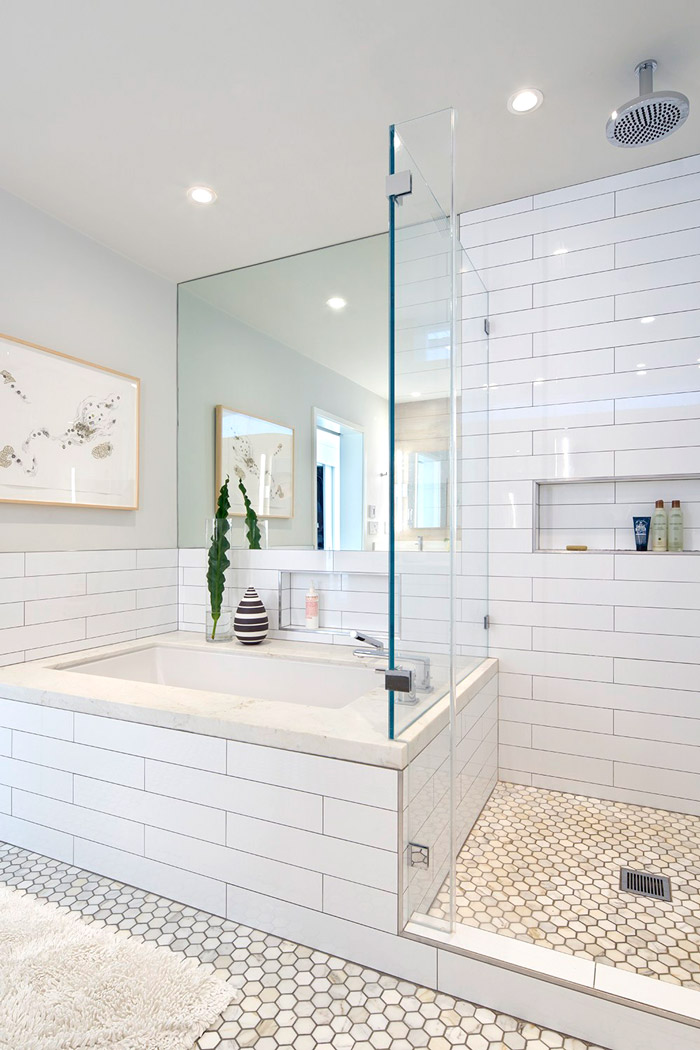 The bathroom is neutral, with subway and hexagon tiles, with a large mirror and it's light and relaxing