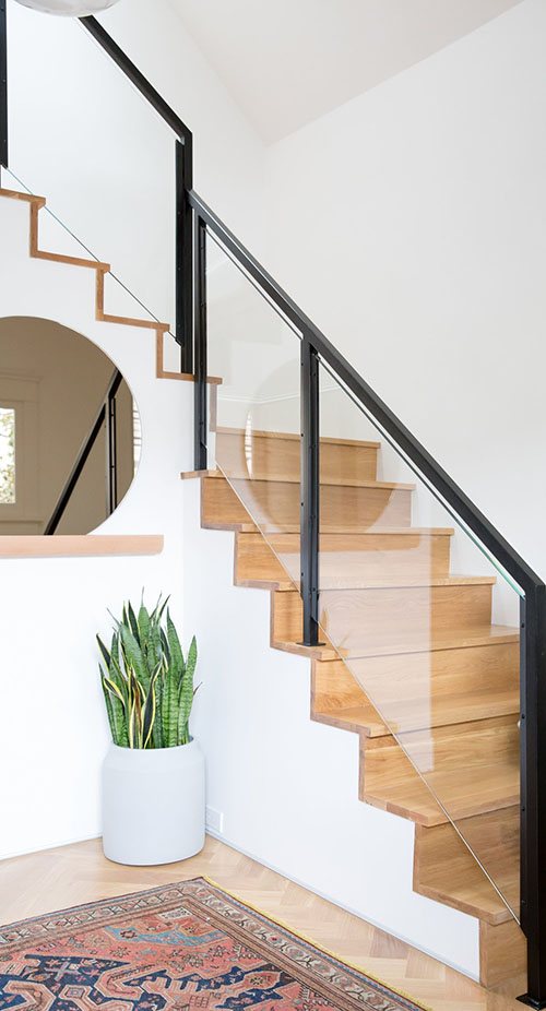 The staircase is also modern, with a black frame and glass banister that makes it super chic