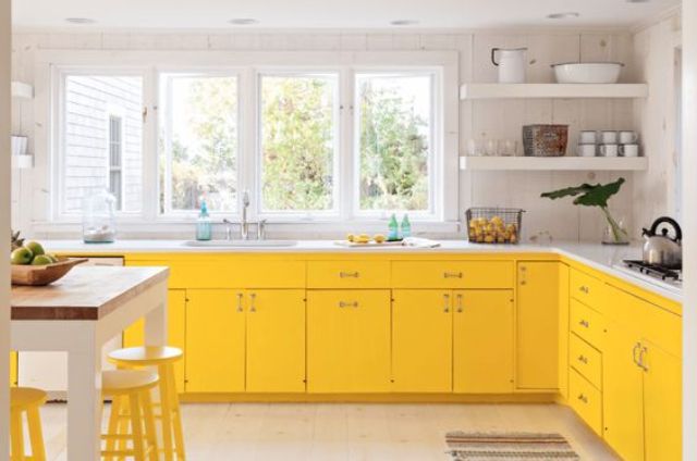 a modern farmhouse kitchen in bold yellow, with white marble counters and yellow stools looks airy and sunny