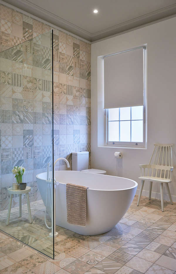 The second bathroom is done with calm-shaded mosaic tiles, a free-standing bathtub and a shower