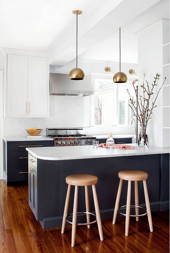 a graphite grey and white kitchen is made more glam with brass lamps and handles