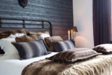 09 a rustic space with a black headboard wall of wood, a faux deer head and lots of faux fur