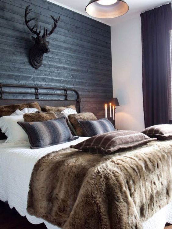 a rustic space with a black headboard wall of wood, a faux deer head and lots of faux fur
