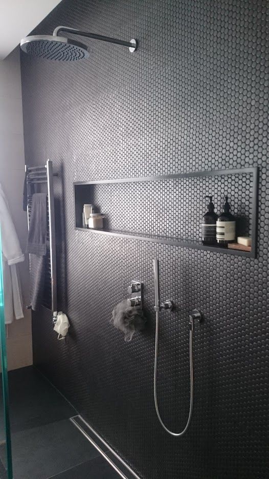 black penny tiles on the shower wall give it a textural look and add eye-catchiness to the bathroom