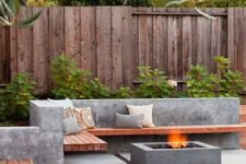 10 a concrete and wood L-shaped bench and a fire pit in a mmodern backyard