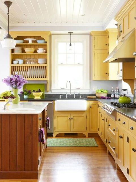 A farmhouse kitchen done in sunny yellow and natural warm colored wood, with dark countertops and open shelving