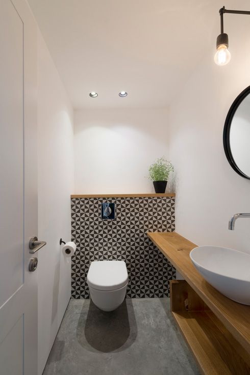 Geometric tile wall accentuates the toilet zone and light colored wood contrasts it perfectly