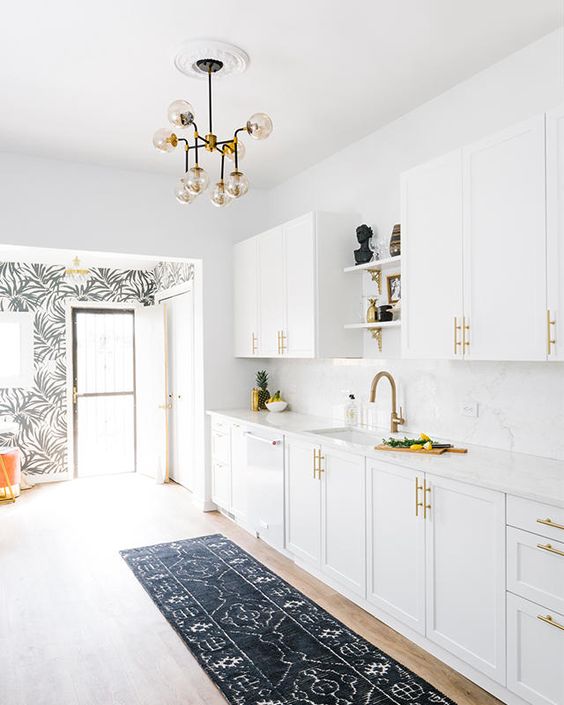 a mid-century modern kitchen done in white, with brass handles and faucets