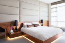 12 a creamy upholstered wall, a floating wooden bed with nightstands with lights coming from below