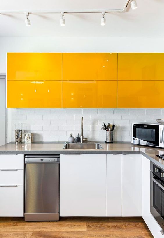 a minimalist yellow and white kitchen with stainless steel appliances and countertops and a subway tile backsplash