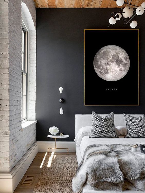 a modern space with an industrial feel is made more interesting with a black wall with an artwork and a white brick wall