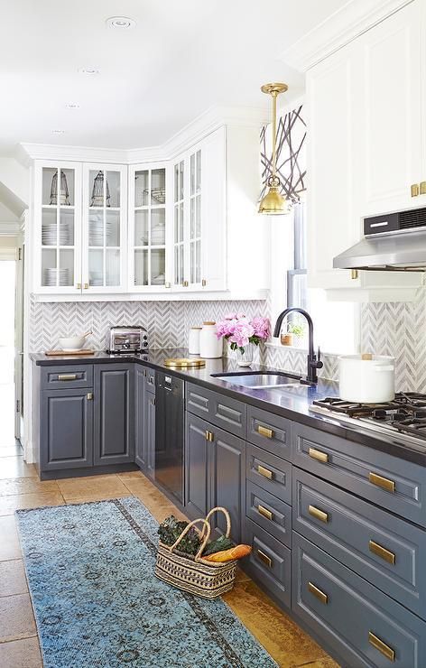 a vintage-styled kitchen with white and grey cabinets, brass touches and a black countertop