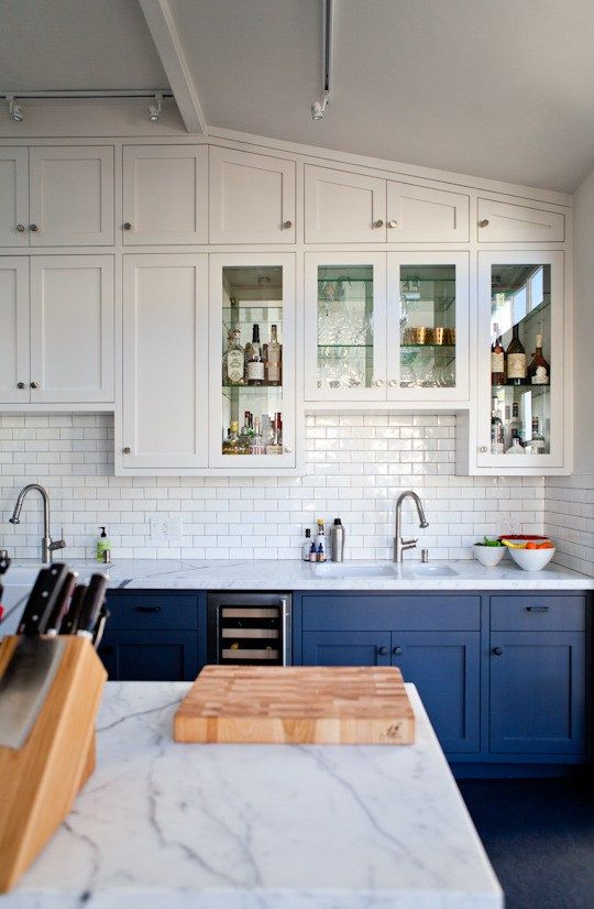 a chic kitchen with white uppers and electric blue lower cabinets plus a subway tile backsplash in white