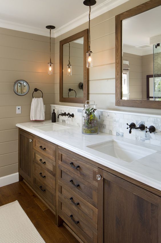 a double stained wooden vanity with a white marble countertop and matching mirror frame