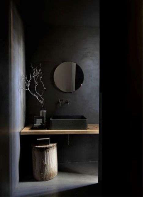 a moody bathroom with black walls and floor, a black sink and a wooden shelf-style vanity