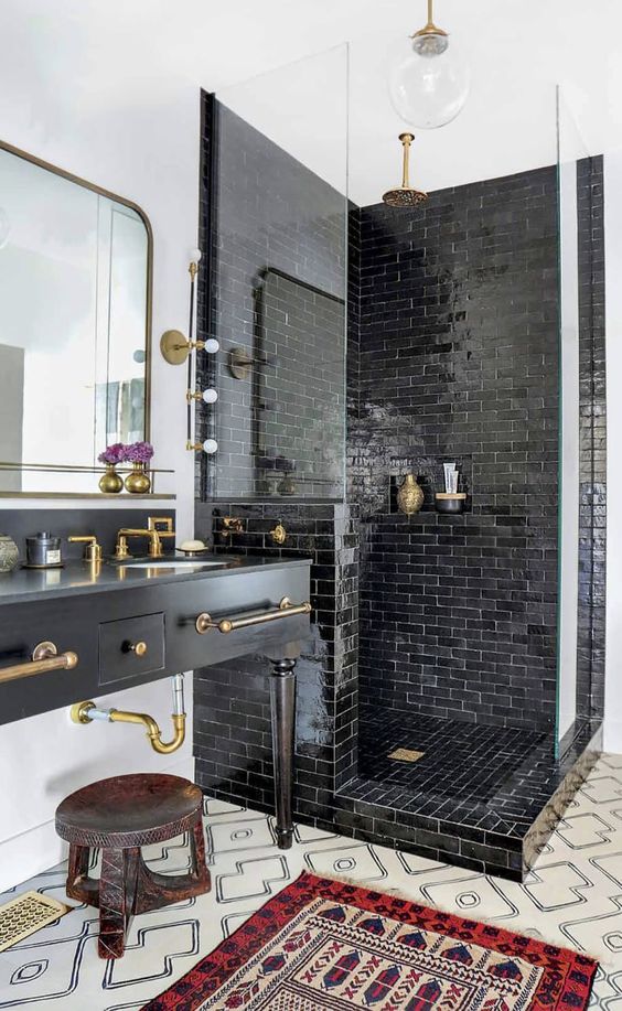 a vintage-inspired matte black vanity with brass fixtures with vintage legs and other brass touches to tying the parts