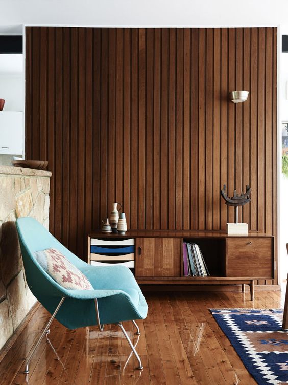 a mid-century modern space with a wood plank wall, matching floor and furniture