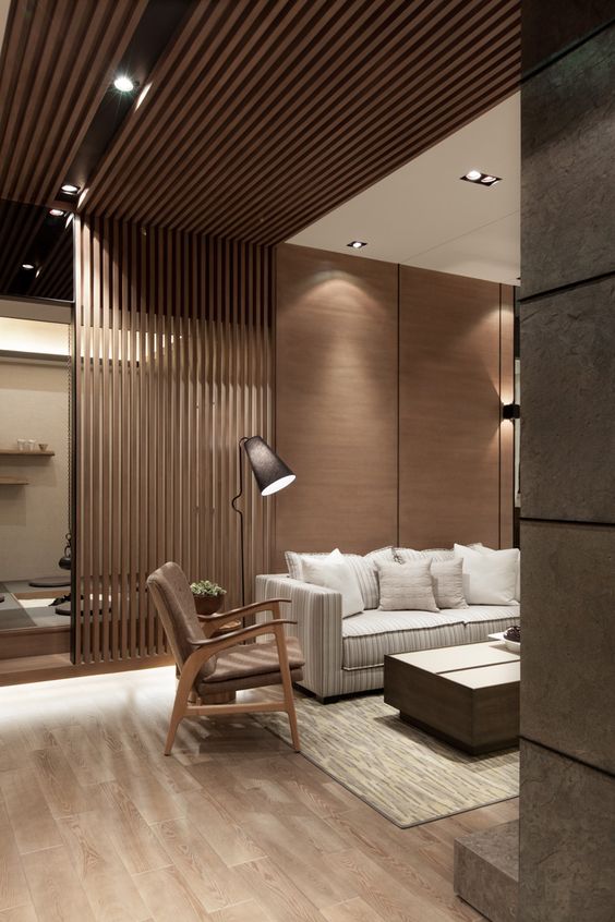 a modern living room with a wooden wall, the part of which is of planks that create a space divider