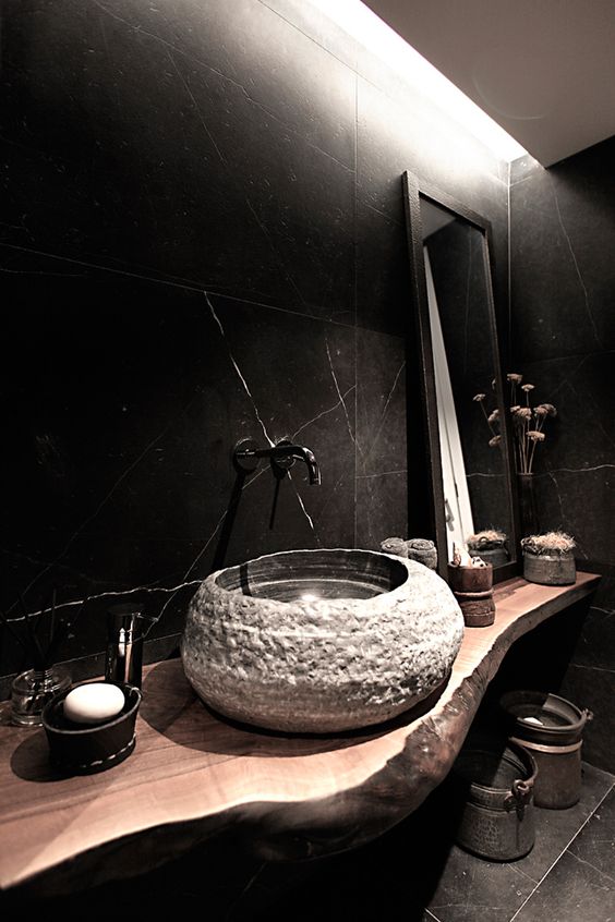 black marble tiles cladding the walls of the bathroom give it a moody feel