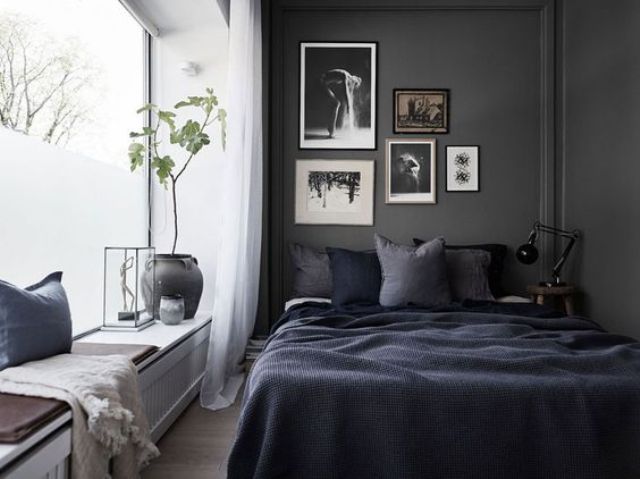 a Scandinavian bedroom is made more relaxing and comfortable with a black wall, and a large window creates a balance betwene dark and light