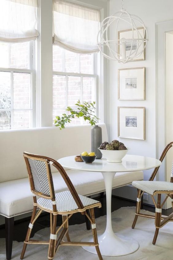 a classic white bench and wicker chairs that make up a cool and cozy breakfast nook