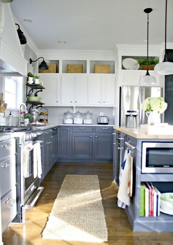 a framhouse-styled kitchen with grey and white cabinets, wicker touches and vintage lamps