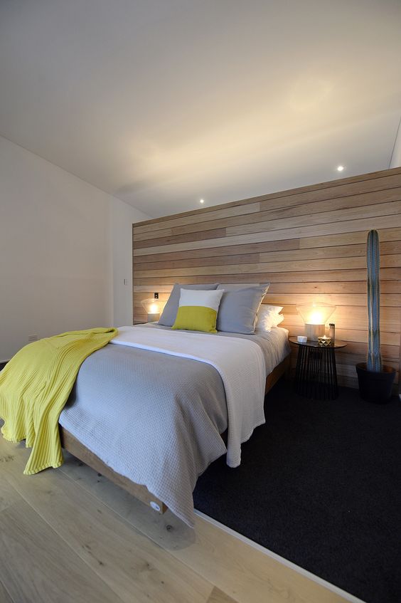 A modern bedroom is completed with a light colored wooden wall and matching floor