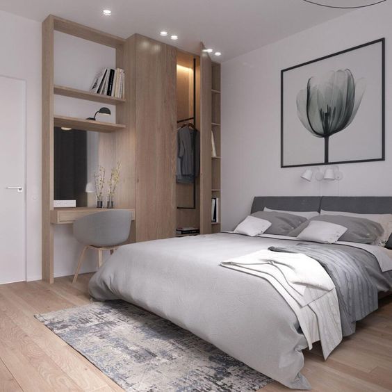 a modern bedroom in white and light grey, wooden floors and a wooden wall item with a wardrobe and desk