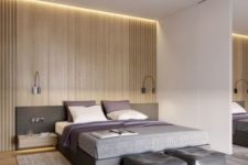 18 a modern space with light-colored wooden wall and floor, an upholstered grey bed with a headboard and grey leather poufs
