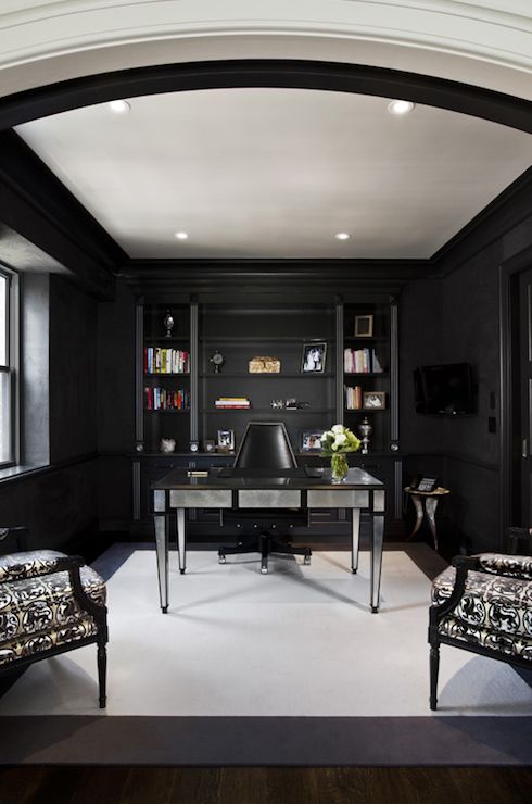 a gorgeous home office with black walls, an open shelving unit and a mirrored desk