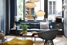 19 a modern space with black walls and furniture, colorful touches and pendant lamps, the space is filled with light and doesn’t seem gloomy