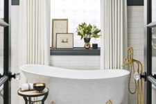 19 a refined crystal chandelier, a bathtub on clawfeet, brass fixtures and creamy curtains add a glam feel to the space