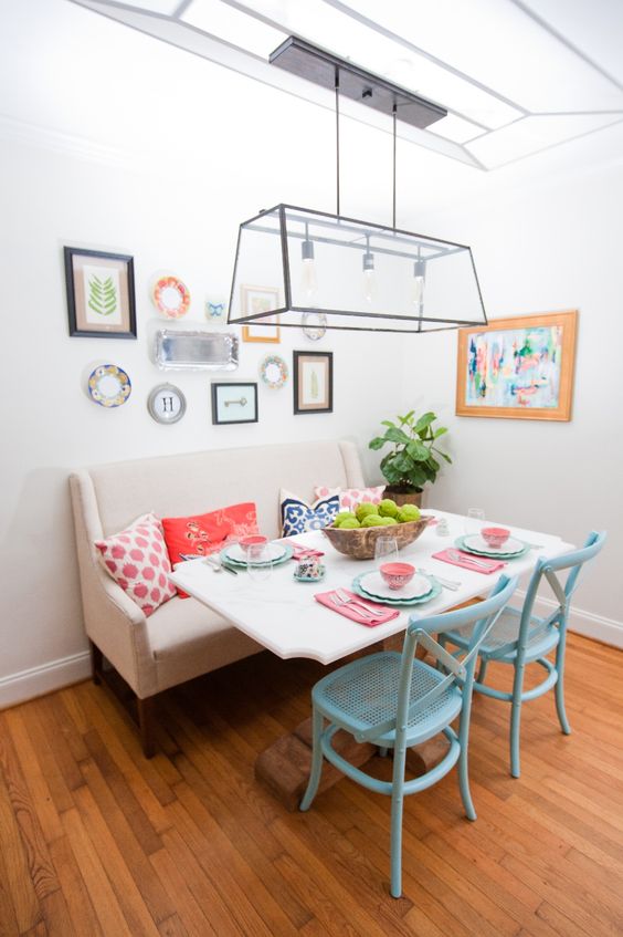 a colorful eclectic dining space with a comfy bench and blue chairs
