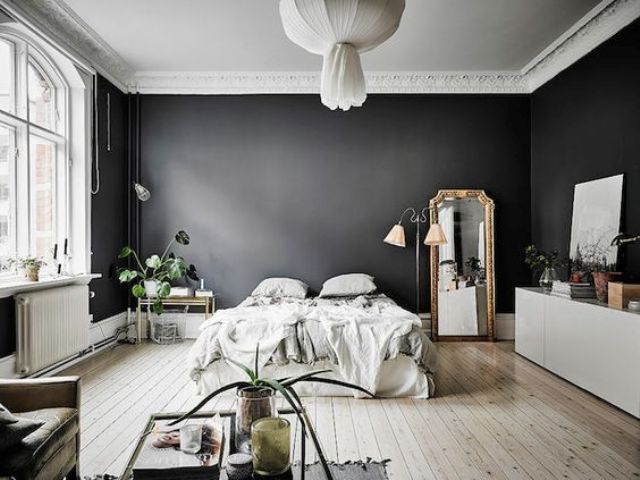 A dramatic Scandinavian space with black walls looks airy thanks to lots of light and light colored wooden floors