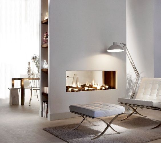 a modern white space with a double-sided glass fireplace for the kitchen and living room