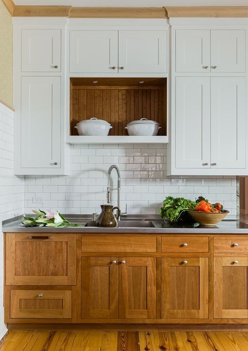 a cozy rustic kitchen with white and wooden cabinets of traditional design and a subway tile backsplash