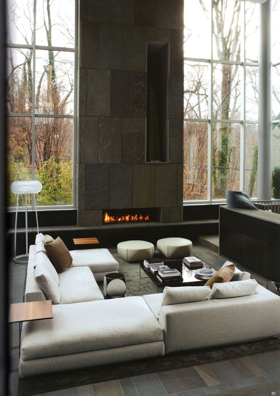 A double height fireplace clad with dark patterned tiles and with vertical firewood storage