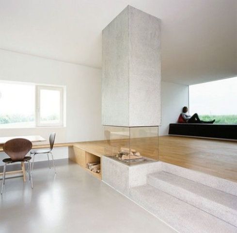 a modern concrete fireplace is a feature of a living and dining space