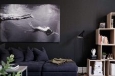 21 a moody space with black walls, a photo artwork, black furniture and a cool rug
