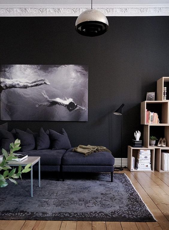 a moody space with black walls, a photo artwork, black furniture and a cool rug