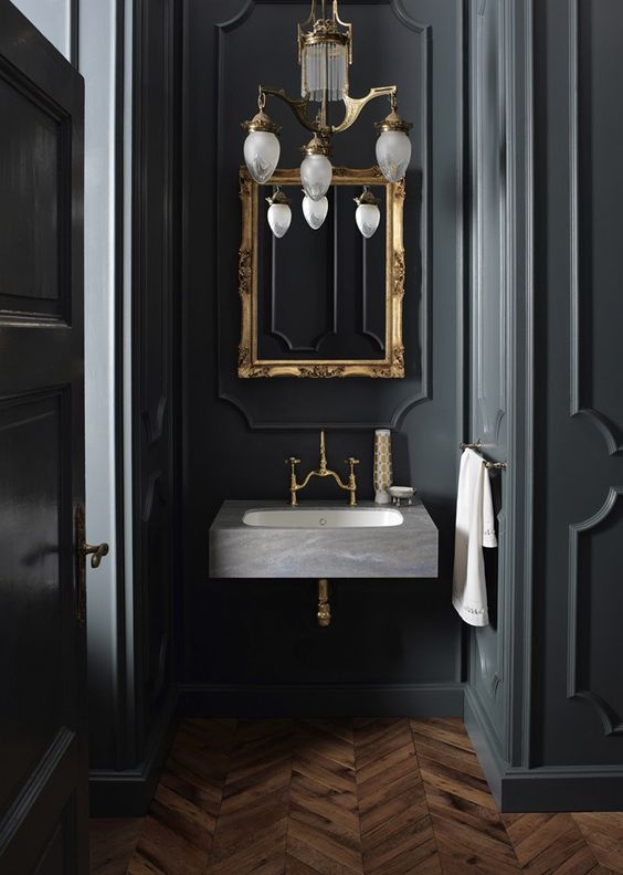 a vintage chandelier, a mirror in a vitnage gold frame and brass fixtures make a cool 1920s moody space