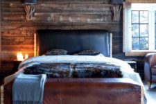 22 a cabin-inspired bedroom with a dark stained wooden wall, a leather bed and a rug that imitates wood slices