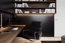 22 a modern masculine space with black wood panel walls and a lit up wall shelving unit, a wall-mounted desk
