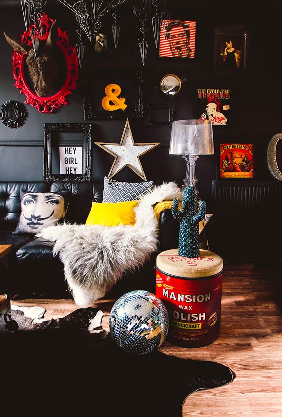 A pop art living room with black walls and furniture and lots of artworks and decorations to make it really eye catching